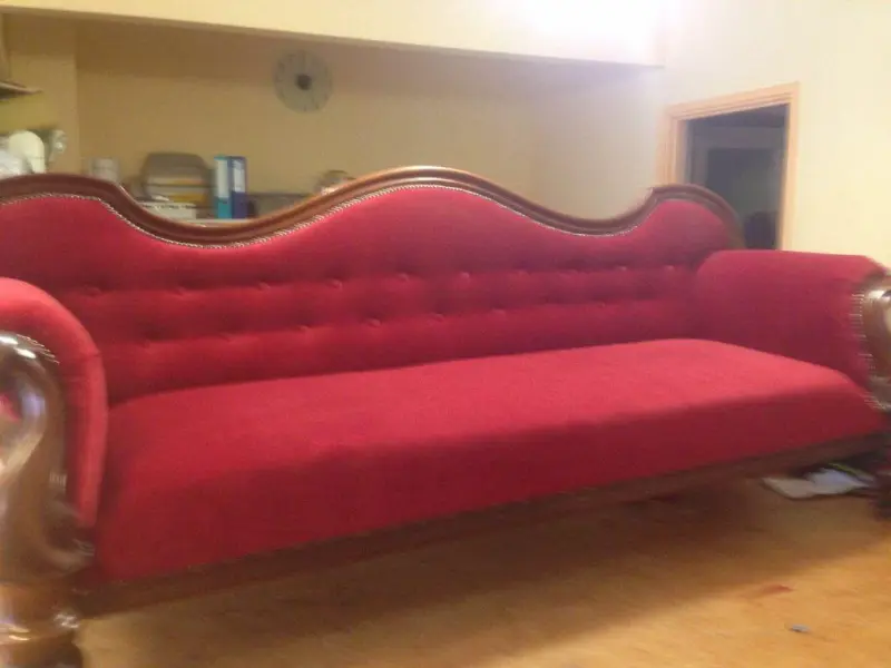 Dezelfde antieke sofa met nieuwe rode capitonné bekleding