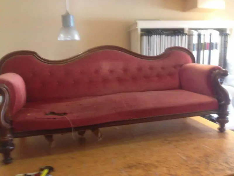 Antieke sofa met versleten rode bekleding